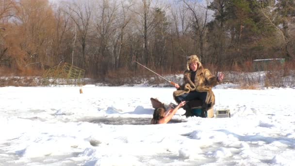 冬には穴の中で泳いでいる女性が氷の下で魚を捕る 彼女は健康を害した — ストック動画
