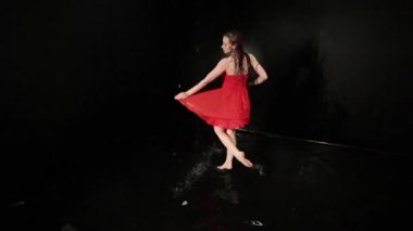 Kırmızı elbiseli bir kadın suda dans ederken döner..