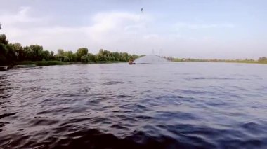 Adam su üzerindeki bir wakeboard 'da spor numaralarını gösteriyor. Wakeboard 'la suyun üzerinden atlıyor..