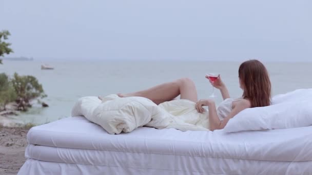 Kobieta Leży Łóżku Nad Morzem Trzyma Kieliszek Wina Dłoni — Wideo stockowe