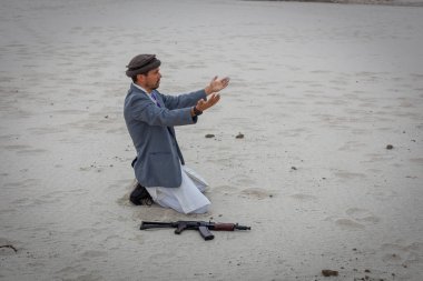 Müslüman adam dışarıda molebeny ayini yapıyor. Silahi yakinda ve savasa devam etmeye hazir..