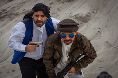 Taliban silahlarıyla terörist saldırılar planlıyor. Elinde silahlarla milli keffiyeden yapılmış başlıklı Arap erkek asker..