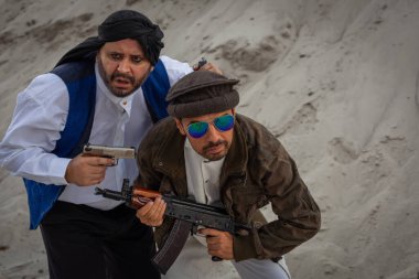 Taliban silahlarıyla terörist saldırılar planlıyor. Elinde silahlarla milli keffiyeden yapılmış başlıklı Arap erkek asker..