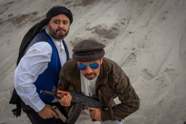 Taliban silahlarıyla terörist saldırılar planlıyor. Elinde silahlarla milli keffiyeden yapılmış başlıklı Arap erkek asker..