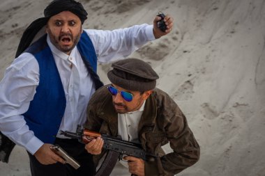Taliban silahlarıyla terörist saldırılar planlıyor. Elinde silahlarla milli keffiyeden yapılmış başlıklı Arap erkek asker..