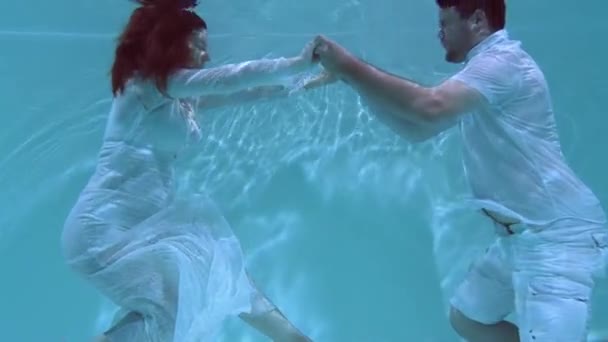 男と女が水中で踊っている 水の下で互いに抱き合って服を着て飛び込む — ストック動画