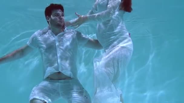 男と女が水中で踊っている 水の下で互いに抱き合って服を着て飛び込む — ストック動画