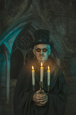 Elinde bir şamdan ile kötü büyücü.
