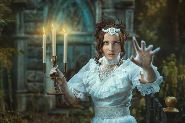 Girl with a candelabra in hand terrifies. — Stock Photo, Image