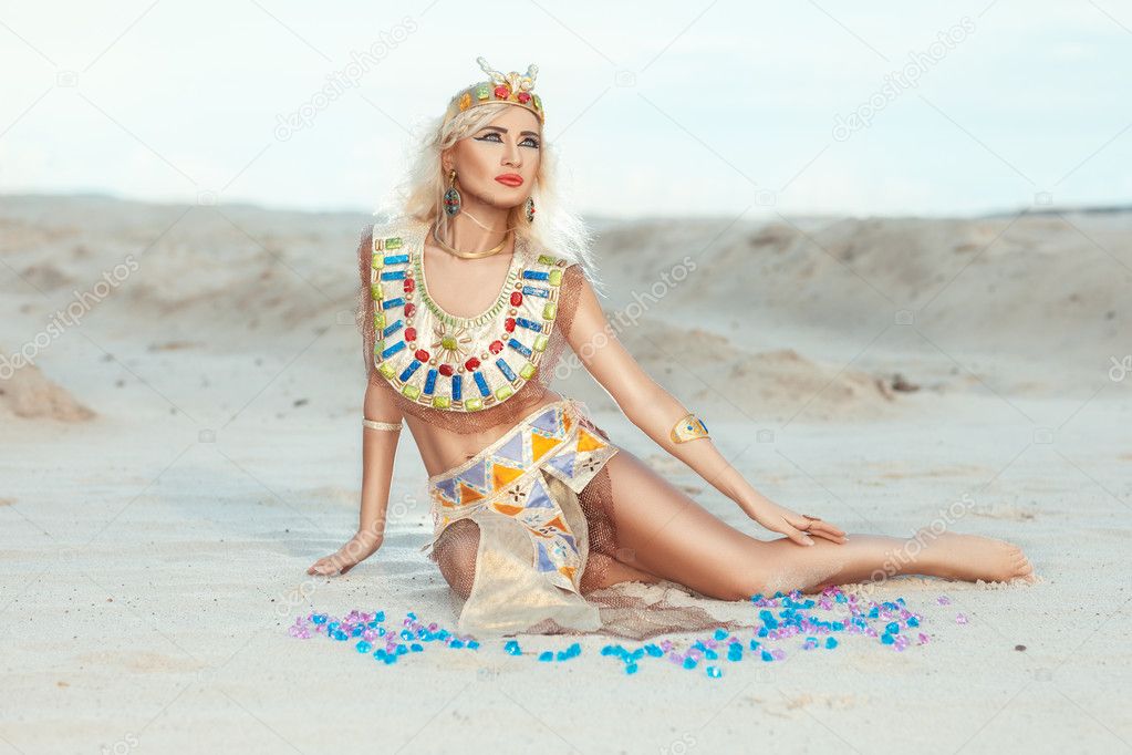 Blonde woman sitting on the sand.