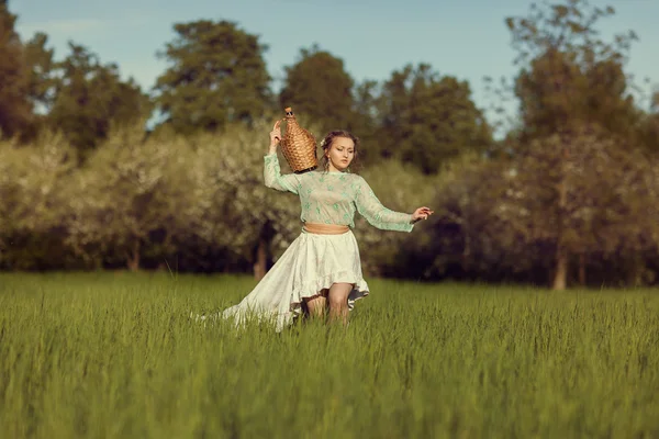 Chica con una jarra está en el campo con hierba . — Foto de Stock