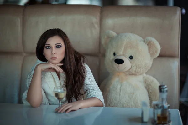 Sad girl at the table with a toy bear. — Stock Photo, Image