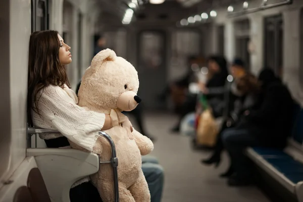 Menina com urso em um carro de metrô . Fotografia De Stock