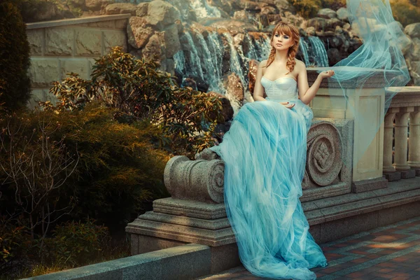 Jong meisje in de buurt van een waterval in de tuin. — Stockfoto