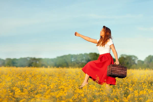 Mädchen mit einem Koffer auf dem Feld. — Stockfoto