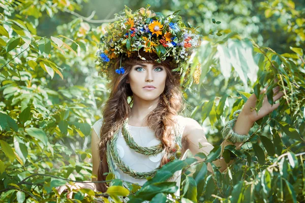 Meisje onder laat bomen met een kroon op zijn hoofd. — Stockfoto