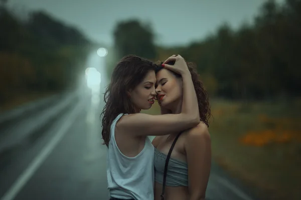 Mädchen stehen auf der Straße im Regen umarmt haben. — Stockfoto