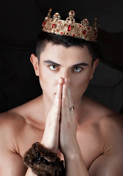 Guy put hands and prays. On head king's crown. — Stock Photo, Image