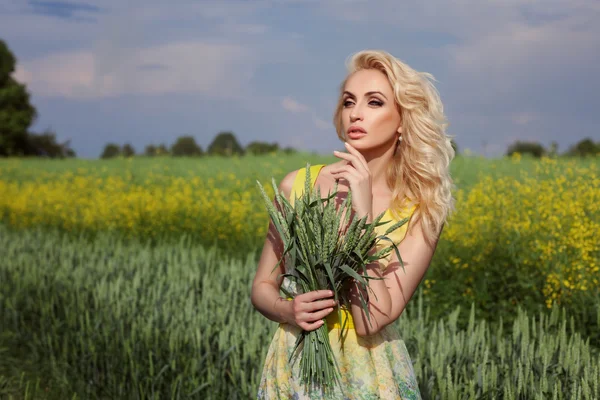 여자는 분야에서 서 있다. 배경, 노란색 꽃에서. — 스톡 사진