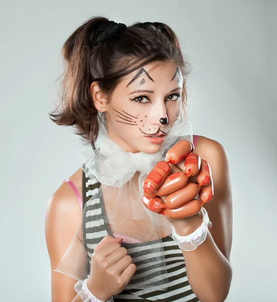 Chica con bozal de gato en su mano sosteniendo salchichas . — Foto de Stock