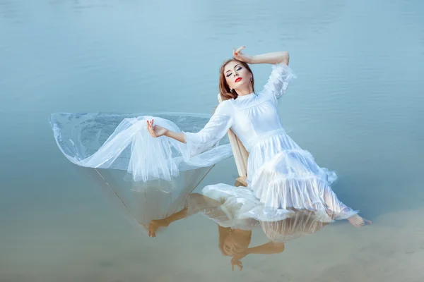 Girl sits on the lake and is reflected surface water. — Stock Photo, Image