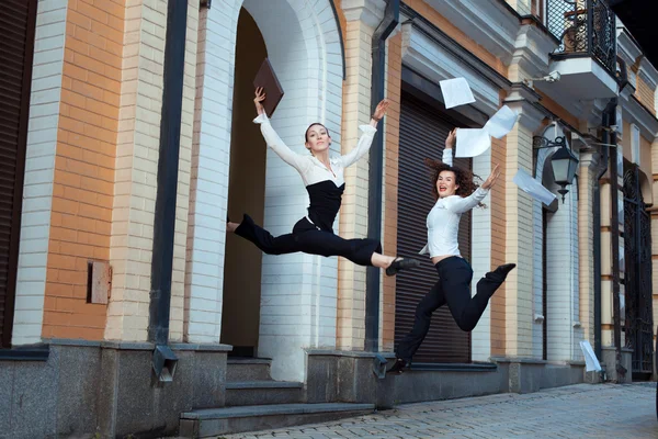 Girls happily jump up and throw papers. — Stock Photo, Image