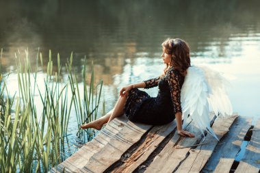 İskeleye Nehri yakınında bir kız melek oturur.