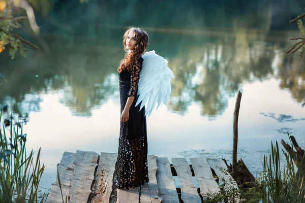 Girl with angel wings standing on the pier and smiling. — Stock Photo, Image