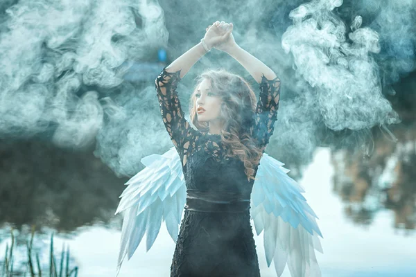 Girl with angel wings is shrouded in smoke. — Stock Photo, Image