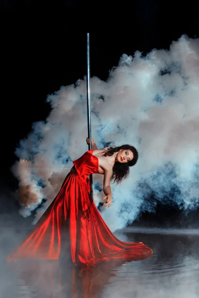 Girl shrouded in smoke dancing around a pole dance. — Stock Photo, Image