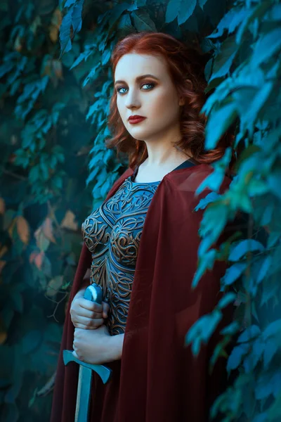 Chica con una espada de pie en los arbustos de uvas . — Foto de Stock