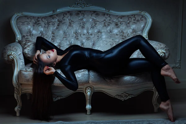 Girl in latex suit is lying on the sofa. — Stock Photo, Image