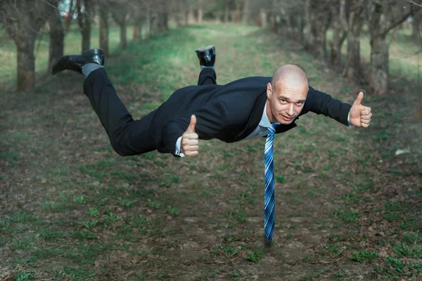 Man in a suit flying the park.