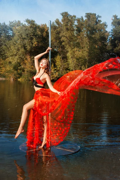 Chica gira en torno a polo bailando en un vestido rojo . — Foto de Stock