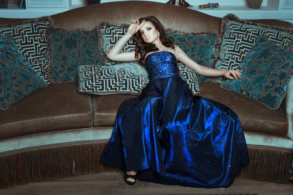 Chica en vestido azul y brillante posando sofá acostado . — Foto de Stock