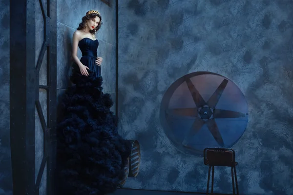 Mujer en un largo vestido negro de pie habitación oscura . — Foto de Stock