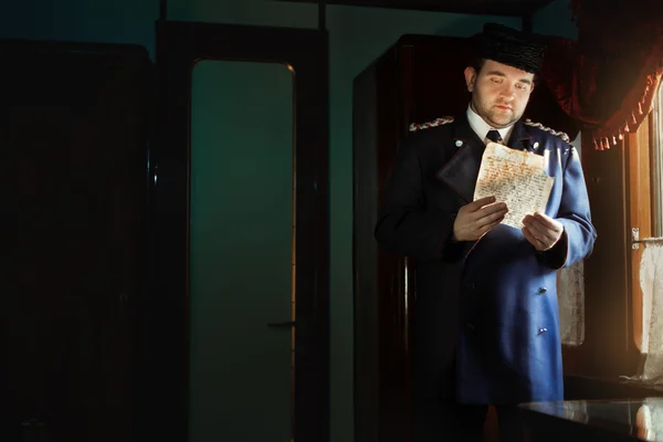 El hombre de uniforme retro está parado en la ventana, sosteniendo el manuscrito . —  Fotos de Stock