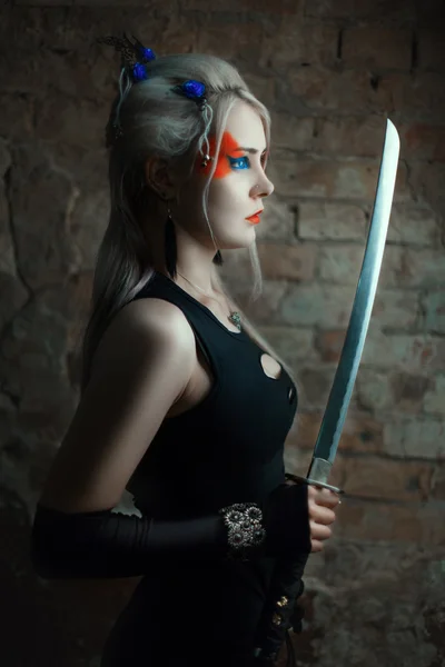 Meisje permanent zijwaarts en houdt zwaard in zijn hand. — Stockfoto
