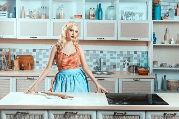 Blonde girl standing in the kitchen next to stove. — Stock Photo, Image
