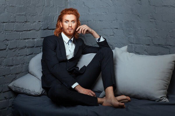 On the bed a man with freckles and red hair.