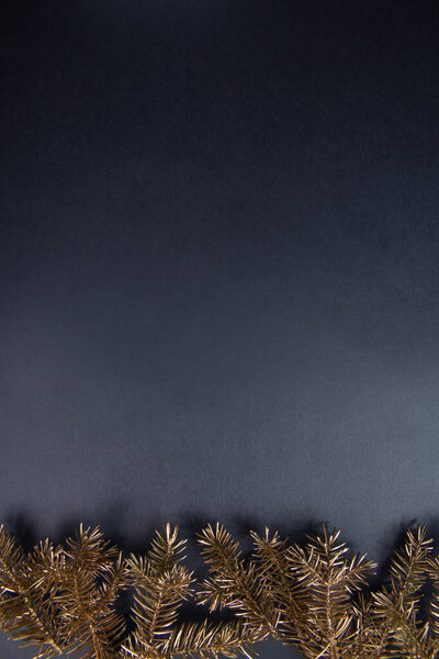 праздничный фон с золотыми еловыми ветками и копировальным пространством