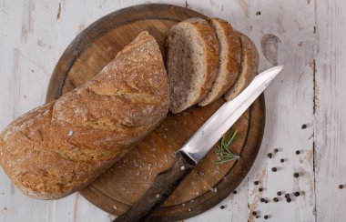 Tahta bir masaya susam tohumları serpiştirilmiş taze beyaz ekmek. Üst Manzara. Mağazadan alınan beyaz ekmek. Doğadan gelen yiyecek.