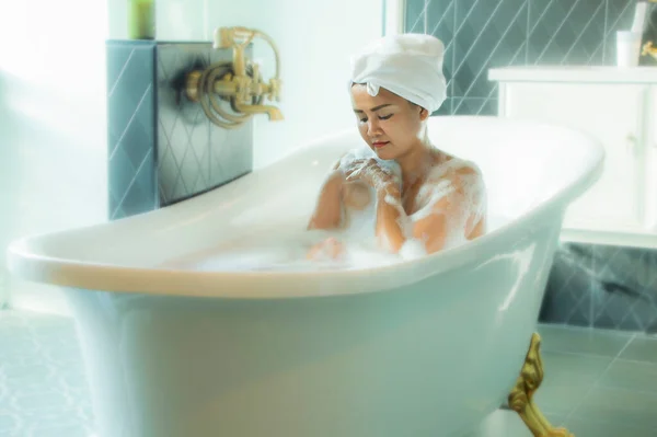 아름다운 이시아 여자는 욕조에 스폰지를 마사지 앞에서 여자는 얼굴에 흥겨운 — 스톡 사진
