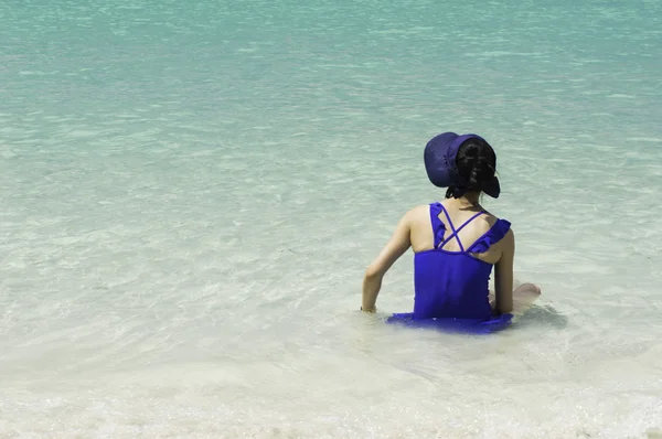 Junges Mädchen sitzt am tropischen Strand und schaut wehmütig zu — Stockfoto