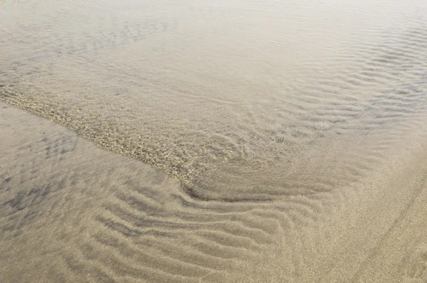 Gros plan d'une petite vague sur une plage ensoleillée — Photo