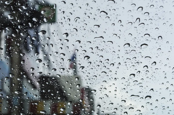 Rain drops on glass with a background — Stock Photo, Image