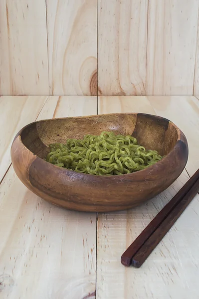 green noodles in bowl on wood table background