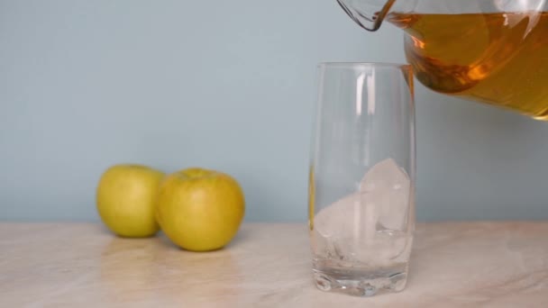 Dans la cuisine, verser le jus de pomme d'une cruche dans un verre. — Video