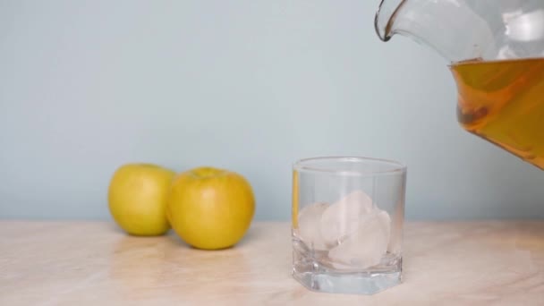 Giet in de keuken appelsap van een kruik in een klein glas. Groene appelen. — Stockvideo