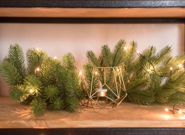 Yeni yıl tatili için stüdyoda dekor. Noel ağacı, ışıklar, mum. Ahşap bir rafta.